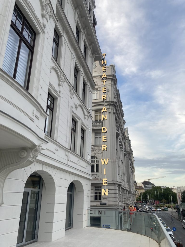Blick von der neu errichteten Besucher:innenterrasse über dem Haupteingang des Theaters, von oben nach unten führt an der Hausecke der Schriftzug „THEATER AN DER WIEN“, rechts daneben ist unten die Linke Wienzeile zu sehen