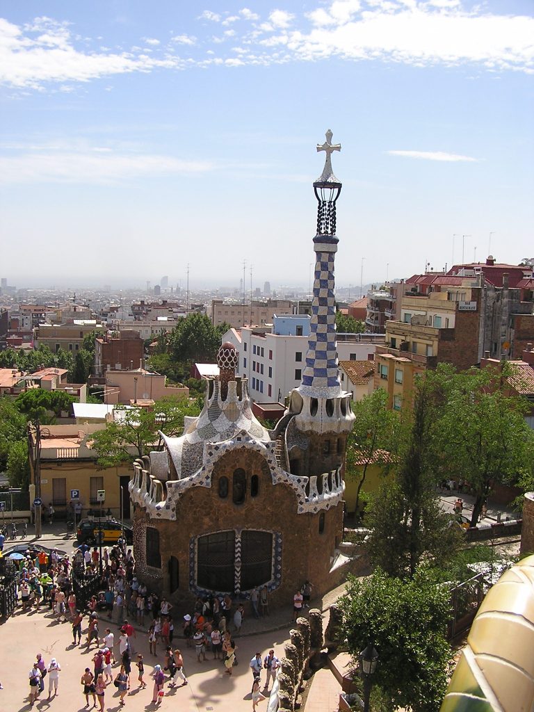 ein Gebäude, dessen Dach wie eine Kasperlmütze wirkt, überragt von einem spitz zulaufenden Turm mit einem Kreuz ganz oben