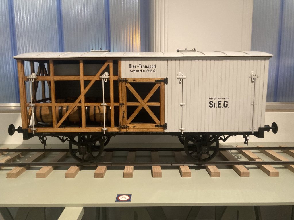 Modell eines Eisenbahnwaggons, der zum Bier-Transport benutzt wurde, der linke Teil der Verkleidung ist offen, dahinter sind stabiliserende Holzbalken und Bierfässer zu sehen
